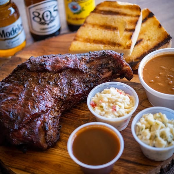 Best BBQ tri-tip, grilled toast, baked beans, coleslaw, and potato salad with beer bottles.